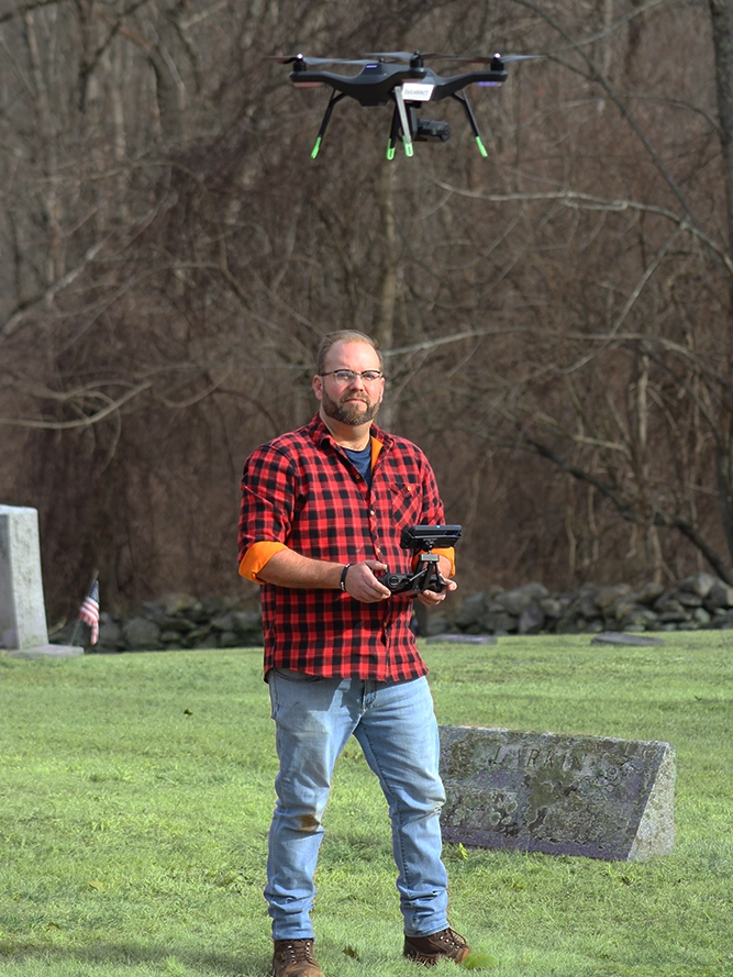 Man flies a drone over grave stones.